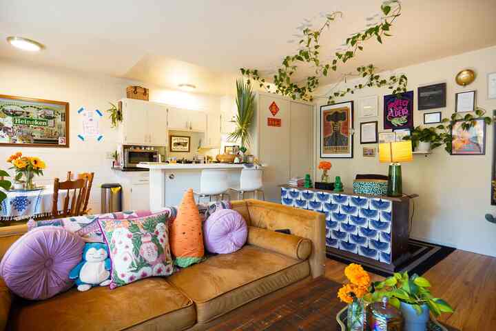Warm brown toned living room featuring patterned cushions and lively plants, creating a vintage and eclectic atmosphere