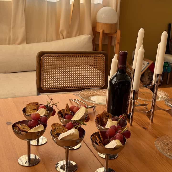 Beige and brown toned dining room featuring wooden table with wine bottle, candles, wine glasses, and appetizers for a cozy home party