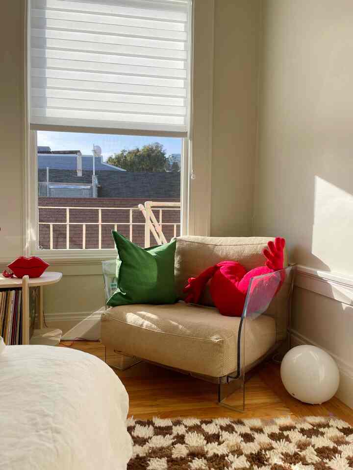 Natural-toned small living corner featuring a beige armchair with green and red cushions in a cozy atmosphere