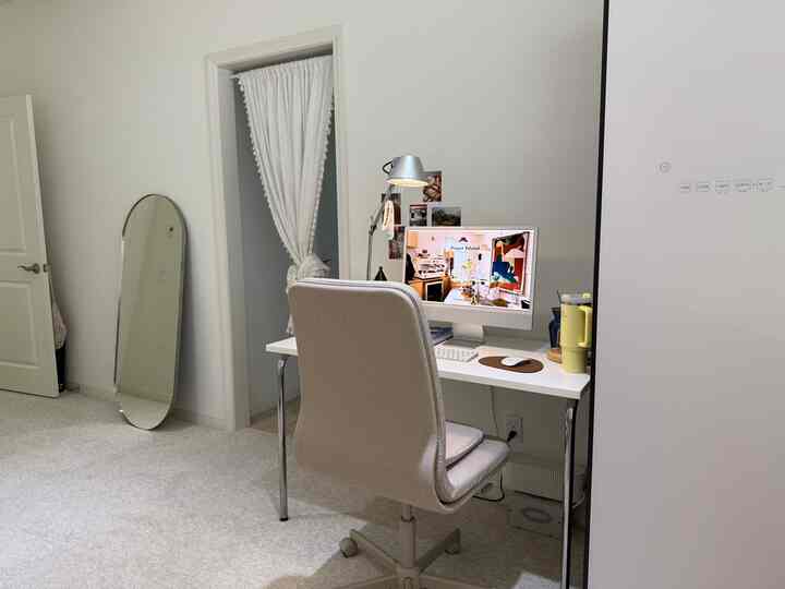 White and beige toned bedroom featuring a compact home office with desk and office chair