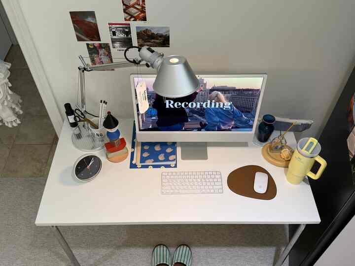 White-toned home office space featuring a desk with computer, keyboard, and table lamp in a clean, cozy workspace