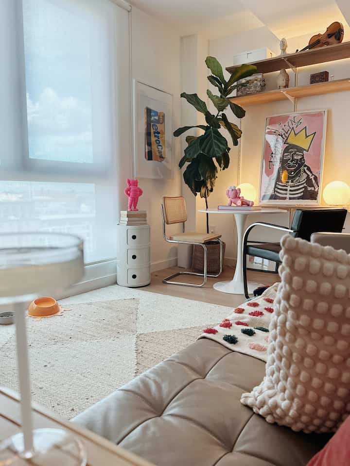 A cozy mid-century modern living and dining room with white and brown tones, natural wood furniture, and a leafy indoor plant