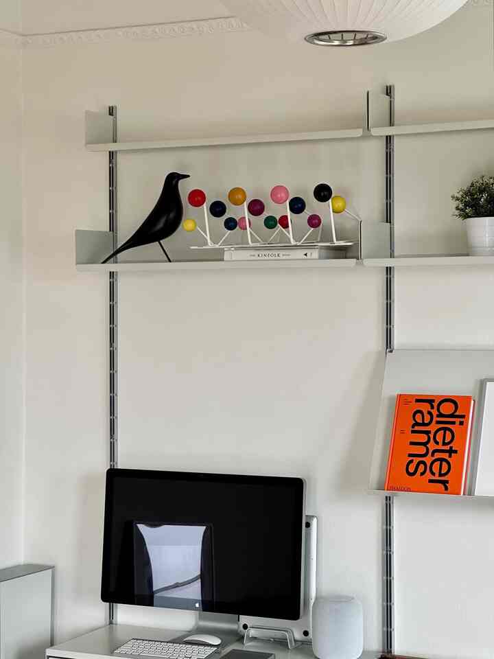 White-toned home office featuring a computer and wall-mounted shelves with a simple and modern design