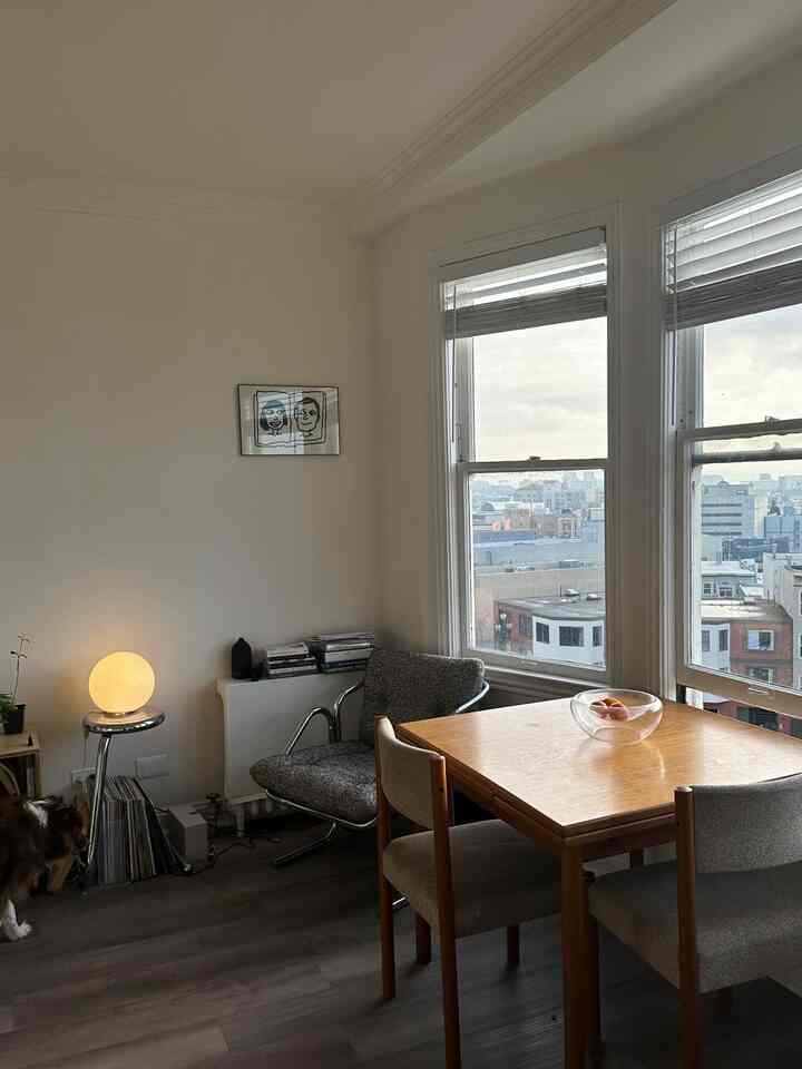 Beige-walled Mid-Century Modern living room featuring a brown wooden dining table and a warm glowing table lamp on a chrome side table