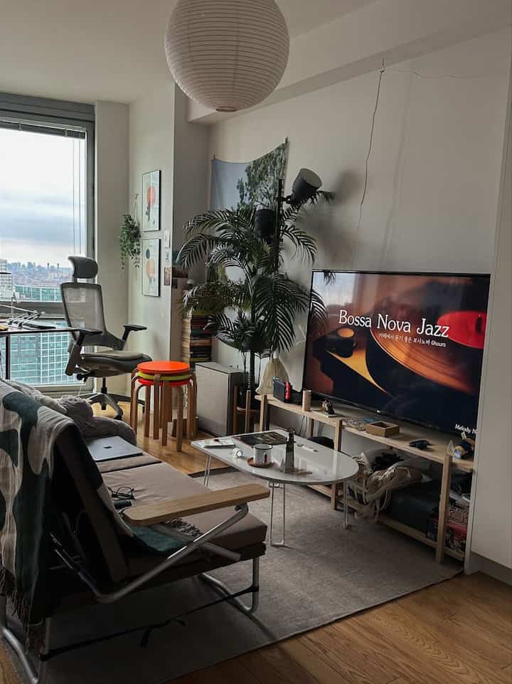 Natural wood tone and gray hues define a small mid-century modern living room featuring a sofa bed, oval coffee table, and TV stand creating a cozy atmosphere