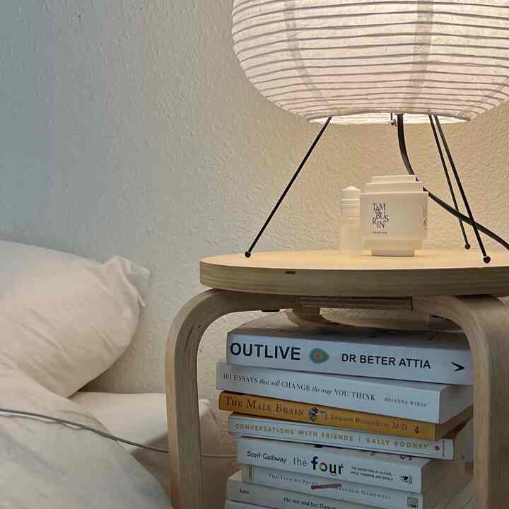 Natural wood tone side table with white bedding in a simple, serene bedroom space
