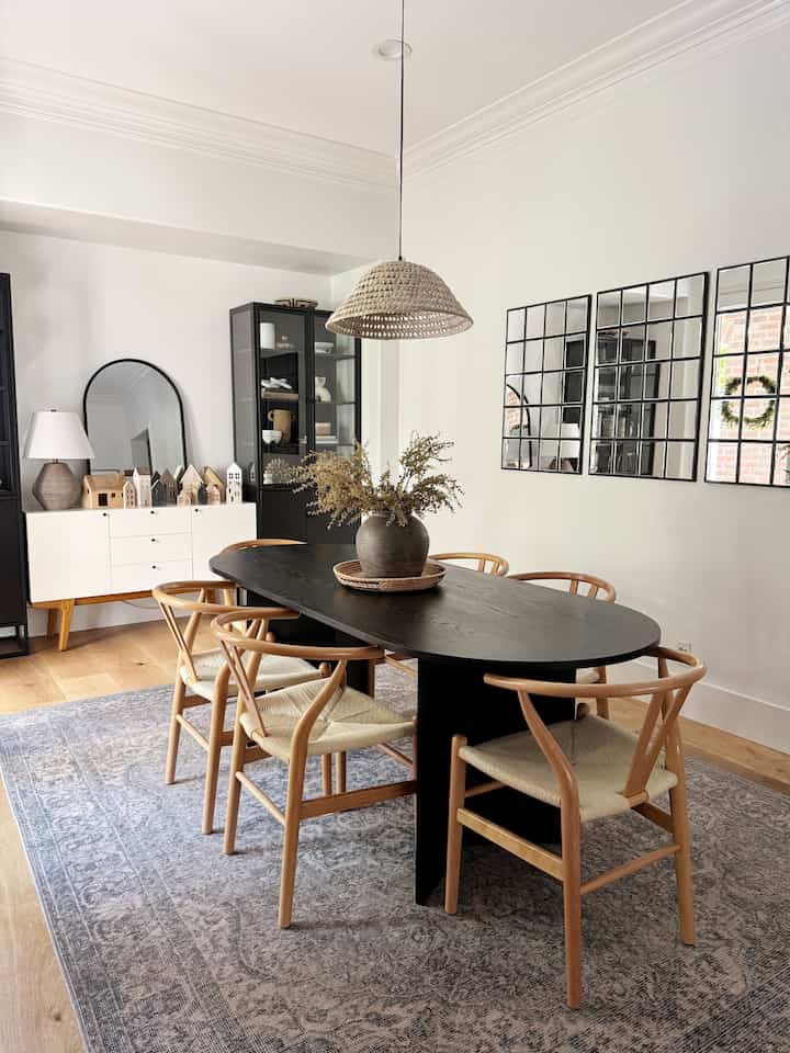Natural wood tones and modern black dining room featuring a black oval dining table with woven chairs, creating a warm and cohesive atmosphere