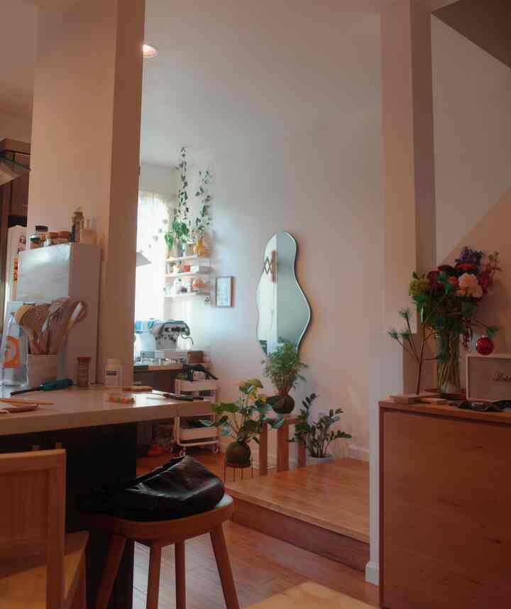 Natural-toned kitchen space featuring wooden elements, an irregular-shaped mirror, and various plants creating a cozy atmosphere