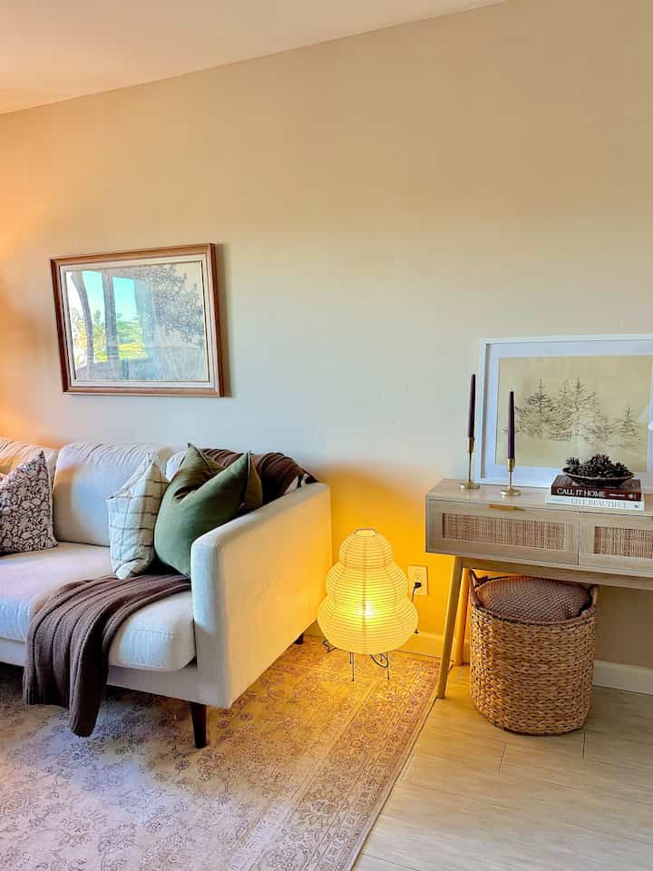 Beige and natural toned living room featuring a minimalist console table, cushions, and a glowing floor lamp creating a cozy atmosphere