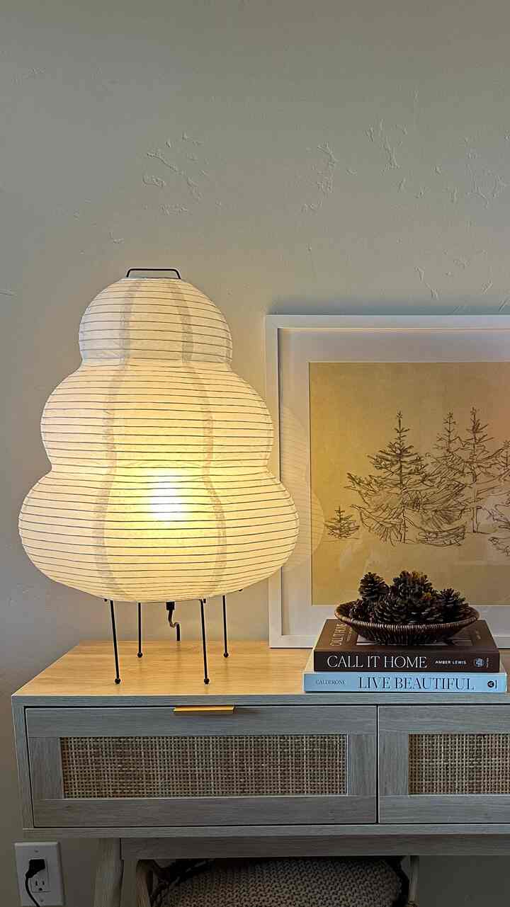 Natural toned living room console table featuring a unique shaped floor lamp and wall art with a calm ambiance