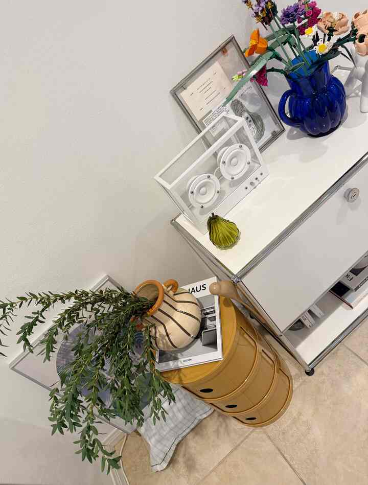Natural color and yellow-toned corner of living room featuring a yellow storage unit, white metal cabinet, and various decorative objects creating a cozy atmosphere
