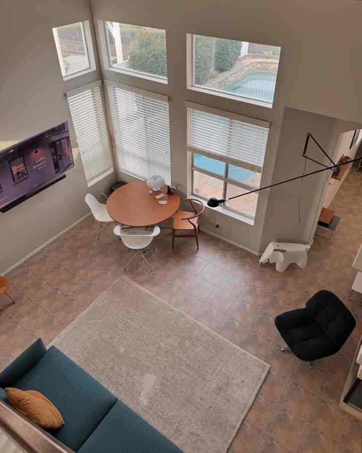 Beige tiled floor and bright walls in a high-ceiling living and dining room featuring mid-century modern furniture