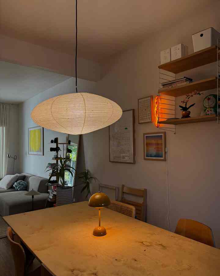Dining room in white and natural wood tones featuring yellow table lamp and wall sconce creating a warm atmosphere