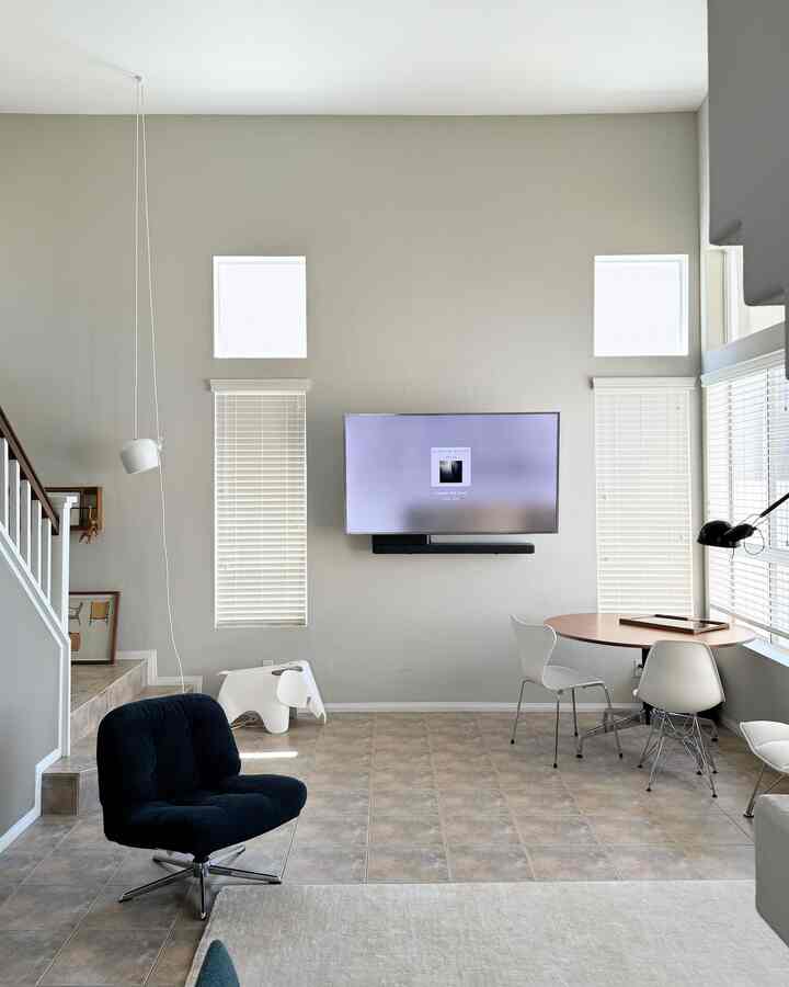 A white and gray toned living room featuring a simple black armchair and round dining table with modern minimalist design