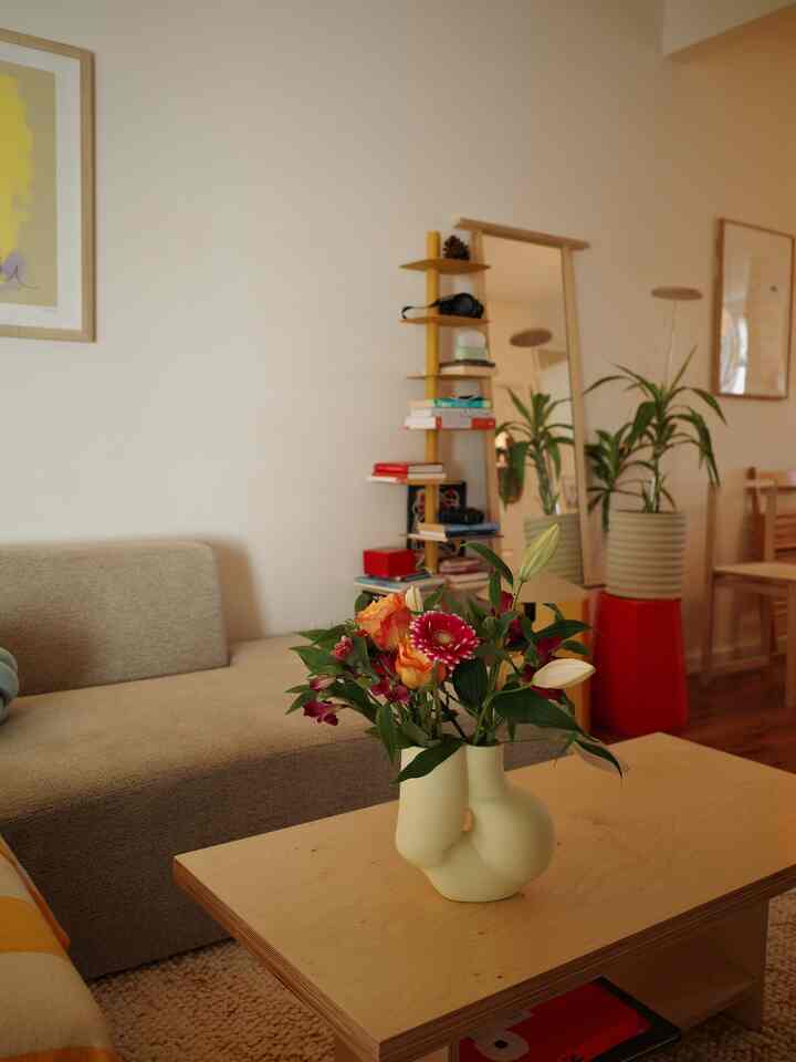 Natural wood tone and beige living room featuring a vase with flowers and plants, creating a cozy mid-century modern atmosphere