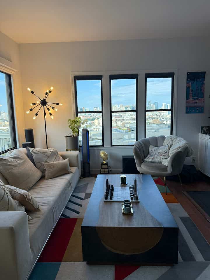 Light brown toned living room featuring velvet lounge chair and sofa positioned by wide windows with a modern aesthetic