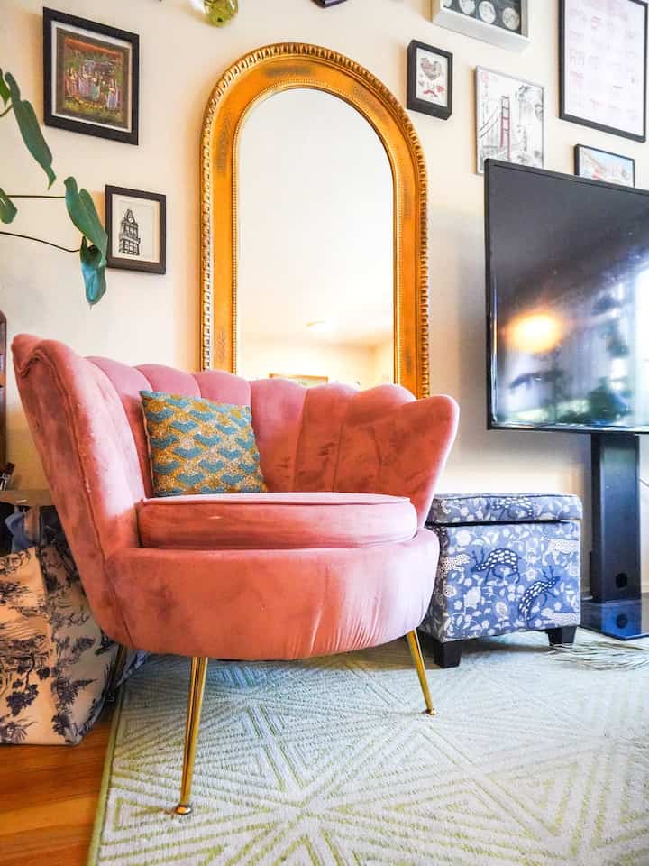 Living room with a pink velvet armchair and gold ornate mirror, stylish and glamorous atmosphere