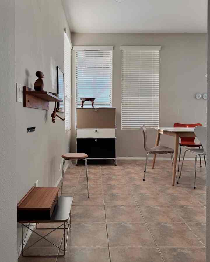 A warm brown tiled mid-century modern dining room featuring a USM cabinet and various chairs arranged in a neat setting