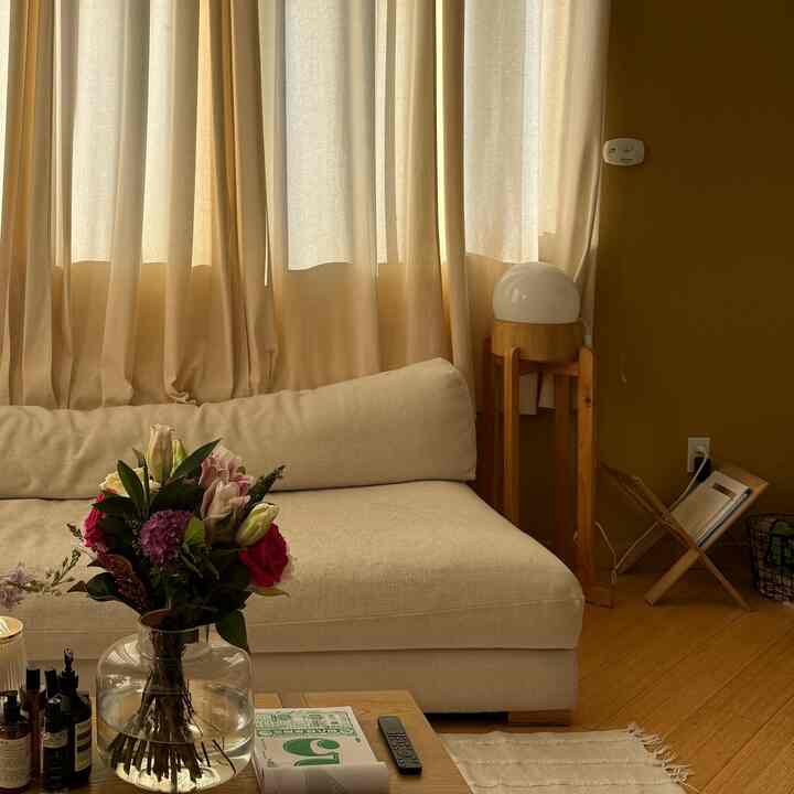 Warm beige-toned living room featuring a beige sofa, wood-toned coffee table, and a vase with flowers in a cozy atmosphere