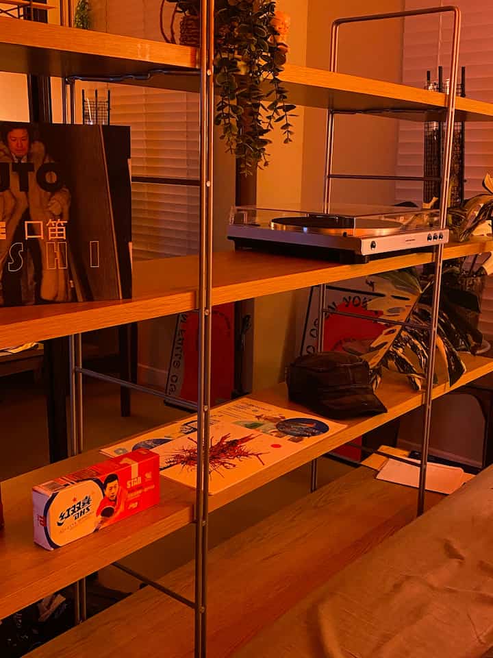 Warm wood tone Japandi living room shelf featuring a Bluetooth turntable and cozy decorative items