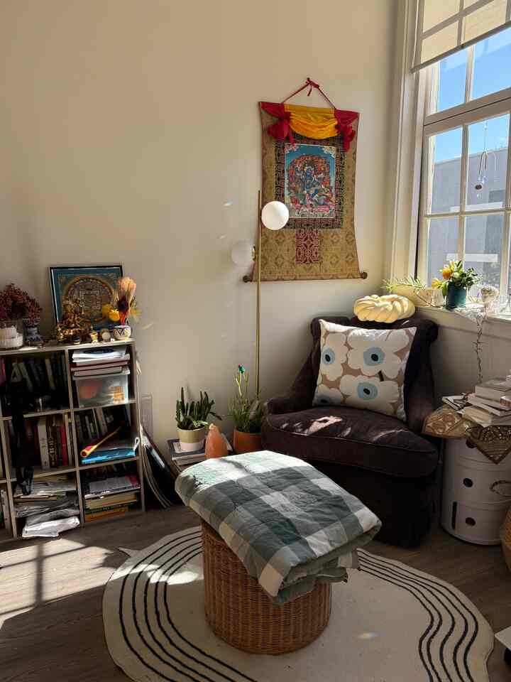 Beige-toned living room reading corner featuring floor lamp, armchair sofa, rug, and plants creating cozy bohemian style interior