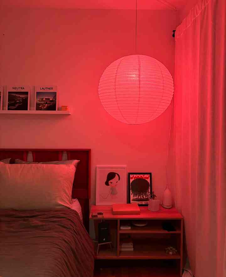 Red-toned bedroom featuring wooden bed and side table with round rice paper lampshade, creating cozy atmosphere