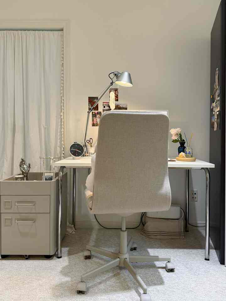 Beige chair and mobile drawer unit in a white-walled compact home office space