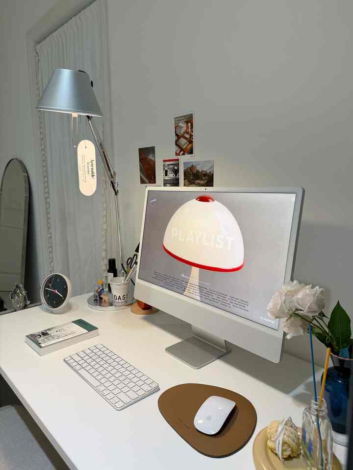 Clean home office space in white and gray tones featuring a white desk with a computer monitor and an Artemide table lamp