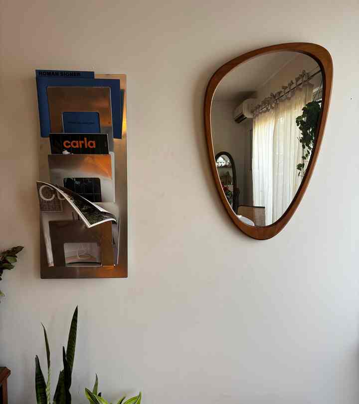 Natural tone entrance with beige walls, wooden framed asymmetrical mirror, and metal magazine rack on wall
