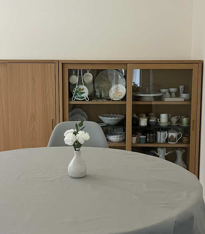 Gray and wood-tone dining room featuring a round table with a vase of white flowers centrally placed, cozy and simple atmosphere