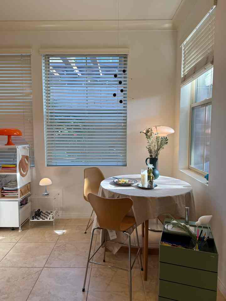 Bright dining room with natural light, featuring wooden chairs and round dining table creating a cozy cafe-style atmosphere.