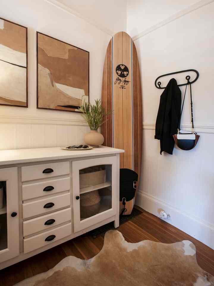 Natural wood tones and white blend in an entrance space featuring a white storage cabinet, framed art, coat rack, and cowhide rug creating a cozy entryway