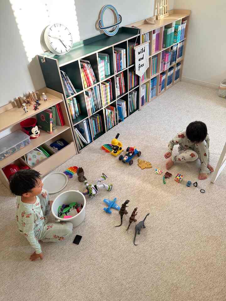 Beige and white toned kids' room featuring toy storage and bookshelves, a cozy natural play space with children