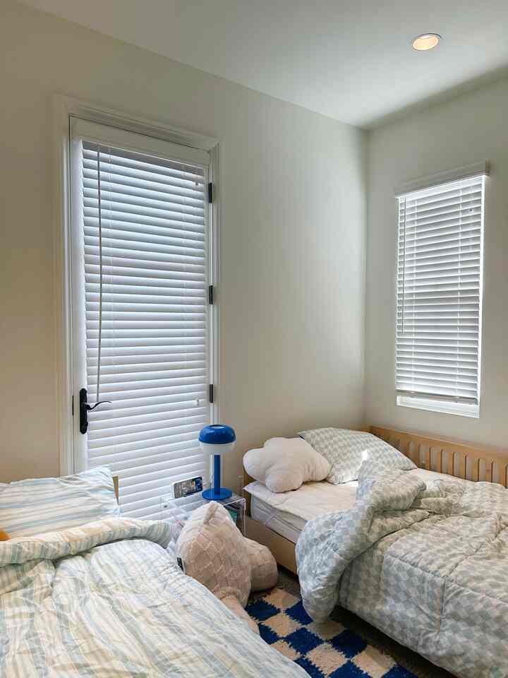 Bright white and blue toned kids' room featuring two beds and a checkerboard rug with cozy atmosphere