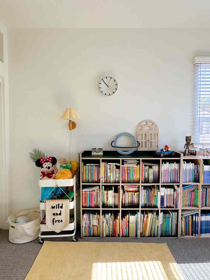 Bright natural-toned kids' room featuring bookshelves and a kitchen cart storing toys and books in a cozy setting