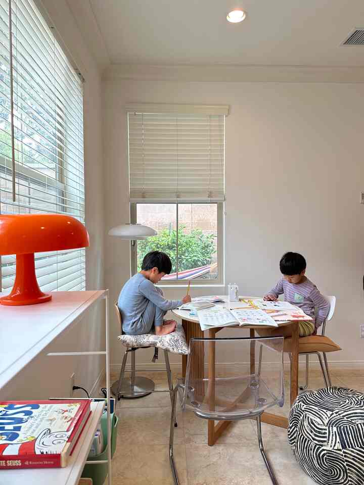 Bright dining room in white and wood tones featuring two kids studying at a round table