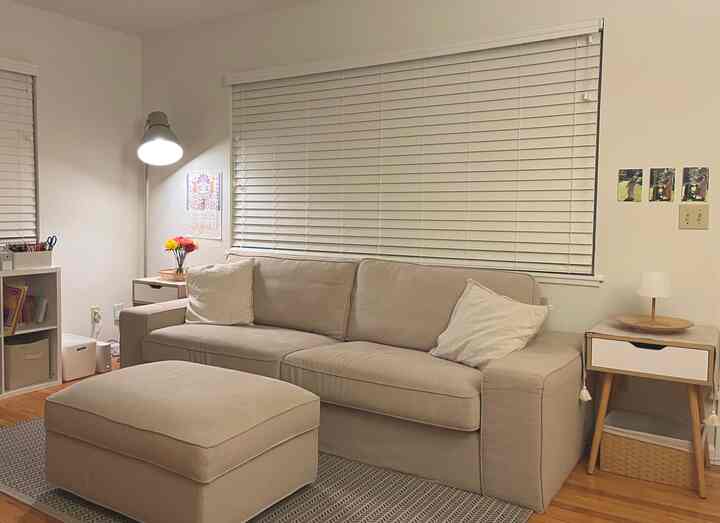 Warm beige-toned living room featuring beige sofa and ottoman with floor lamp creating a cozy atmosphere