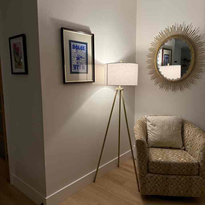 Natural tones and gold accents highlight a cozy study corner with a patterned armchair and gold tripod floor lamp creating a warm atmosphere