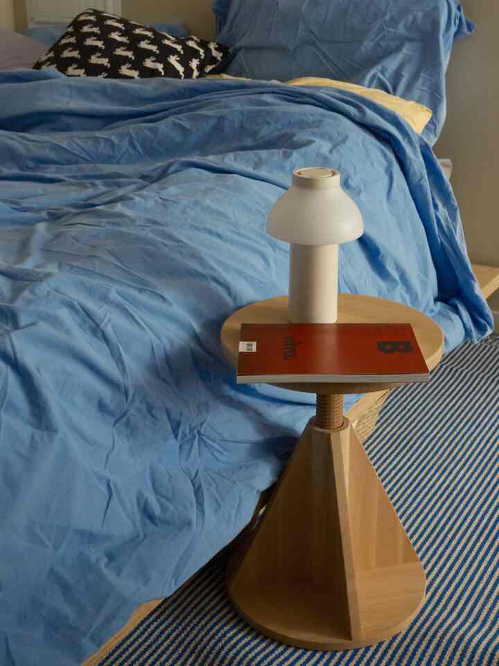 Blue-toned bedroom with wood-tone side table and table lamp, creating a cozy atmosphere