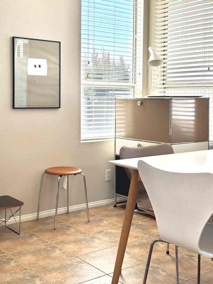 Bright dining room with white and natural color tones featuring a dining table, stool, and cabinet with clean atmosphere