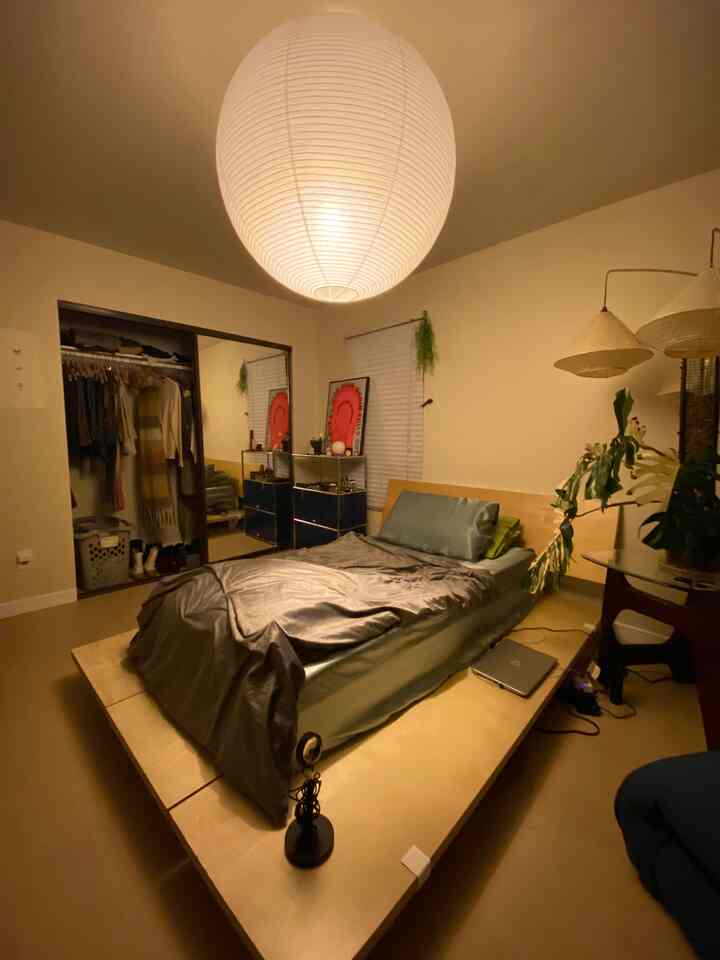 Natural color and wood tone bedroom featuring a large round pendant light and minimalist bed frame with a cozy atmosphere