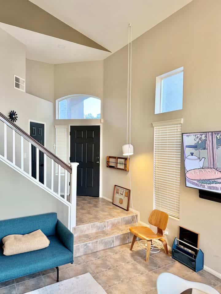 Beige-toned living room featuring a teal sofa and mid-century modern wooden chair with a cozy atmosphere
