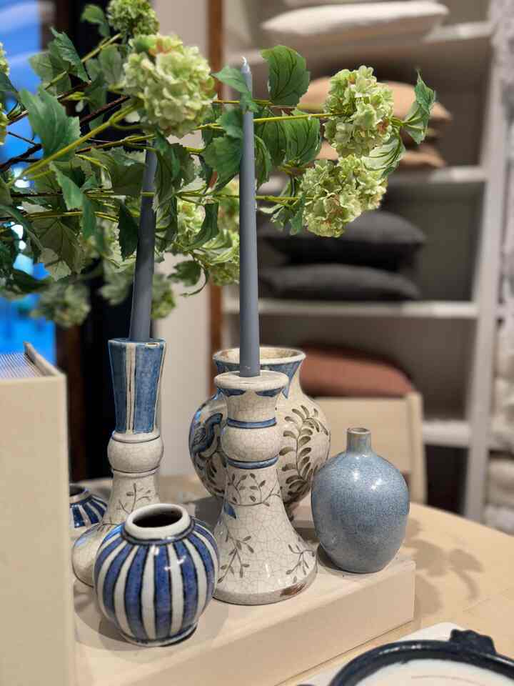 Elegant and serene bedroom decor featuring a collection of ceramic vases in various shapes and blue hues, complemented by delicate green floral accents. #BedroomDecor #VaseCollection #BlueAccents #SereneSpaces
