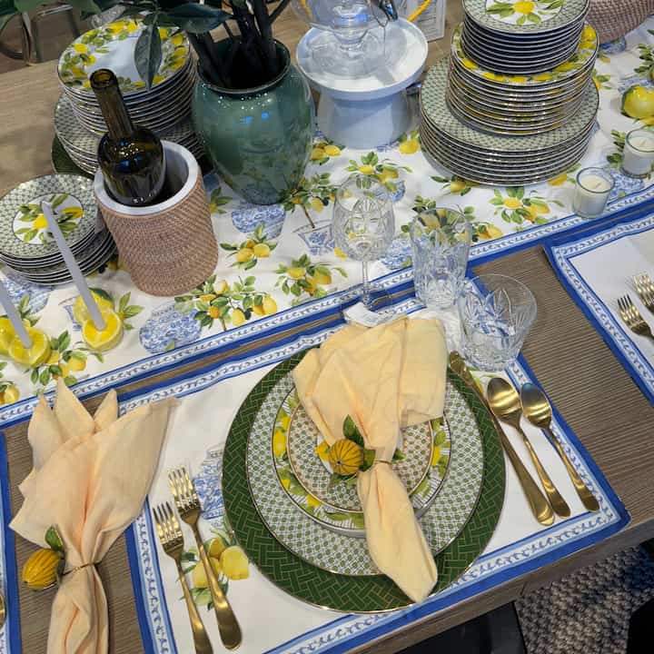 Elegant table with lemon-patterned dishes and gold cutlery set on a bright yellow, green, and blue tablecloth