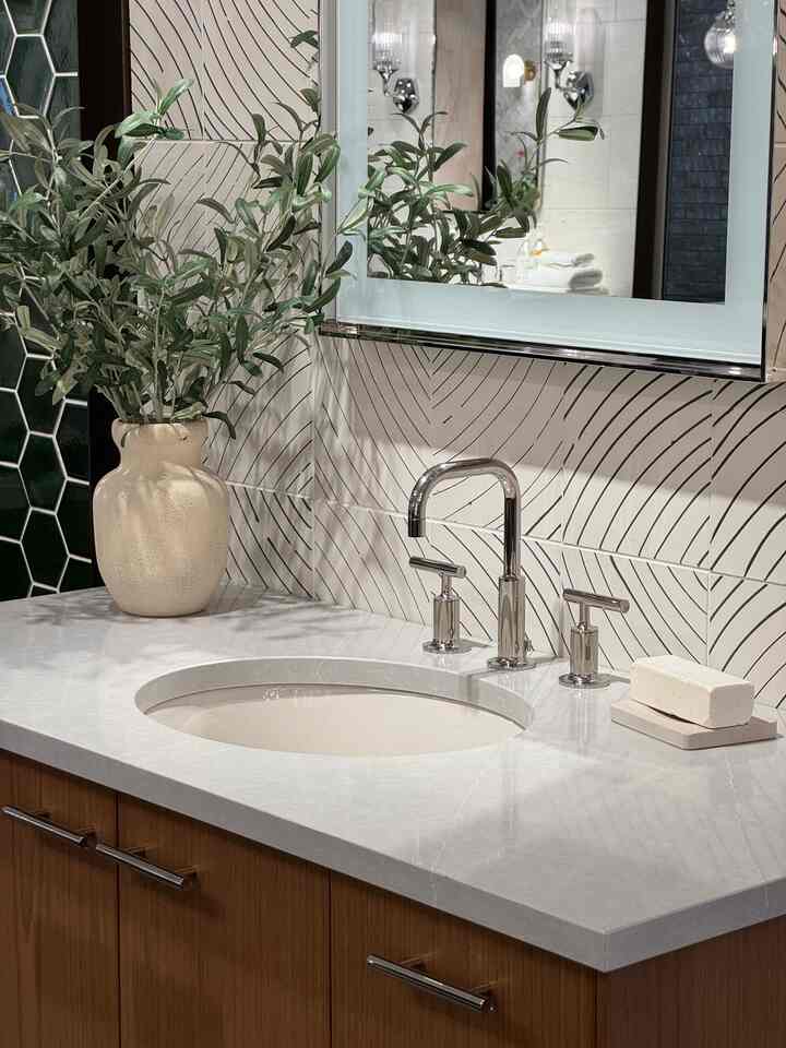 Natural-toned bathroom featuring a wash basin, mirror, and olive plant creating a calming atmosphere