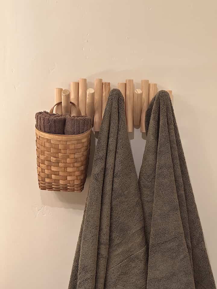 Natural wood tone bathroom featuring brown towels hanging on a towel rack and a stylish wooden basket, creating a cozy atmosphere