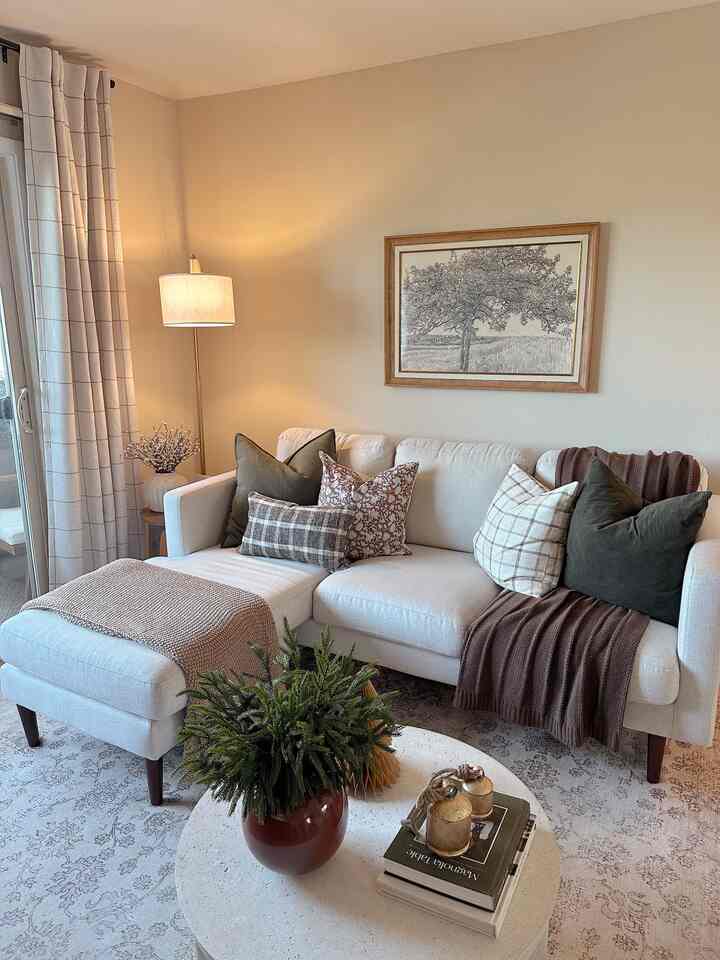 Ivory and brown toned living room featuring a white sectional sofa and round coffee table creating a cozy atmosphere