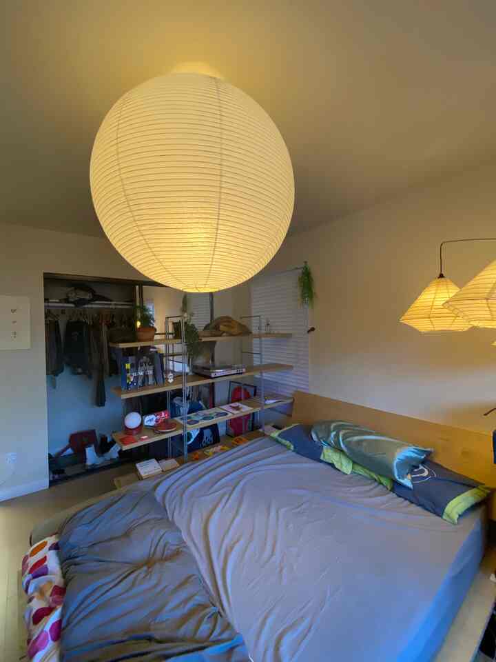 Natural color and wood tone bedroom featuring a bed frame and Akari pendant light in a minimalistic setting