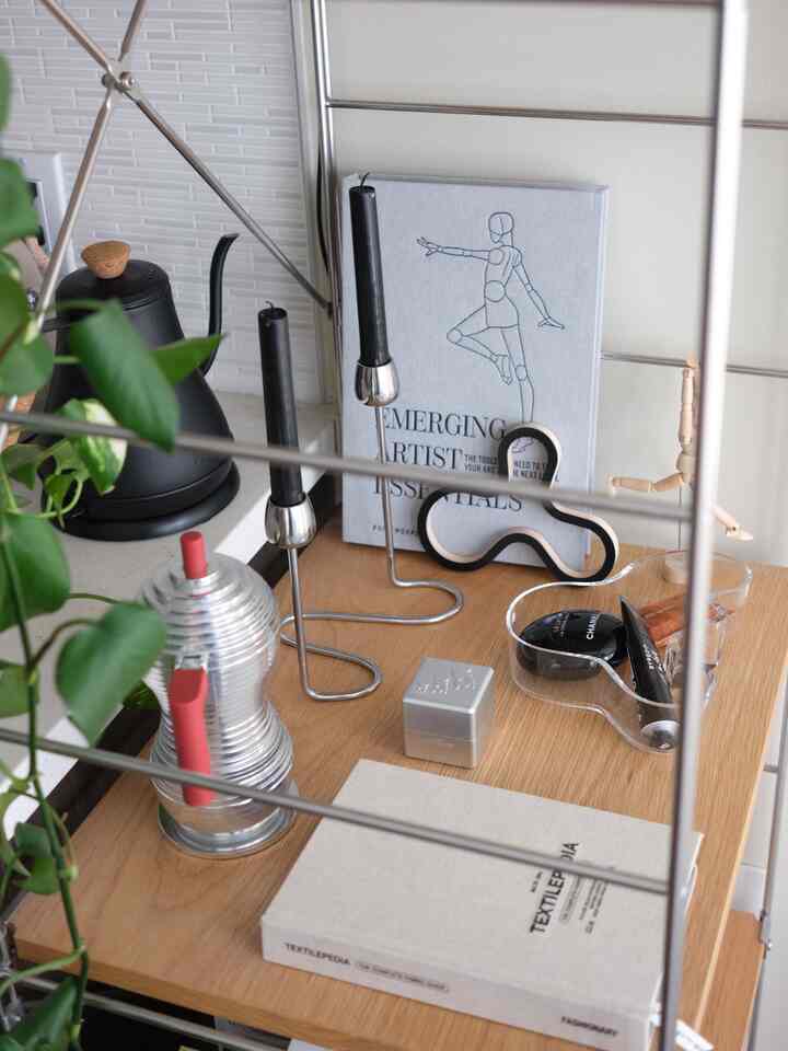 Natural wood-tone shelf featuring silver candlesticks, black kettle and coffee grinder arranged in a tidy storage space