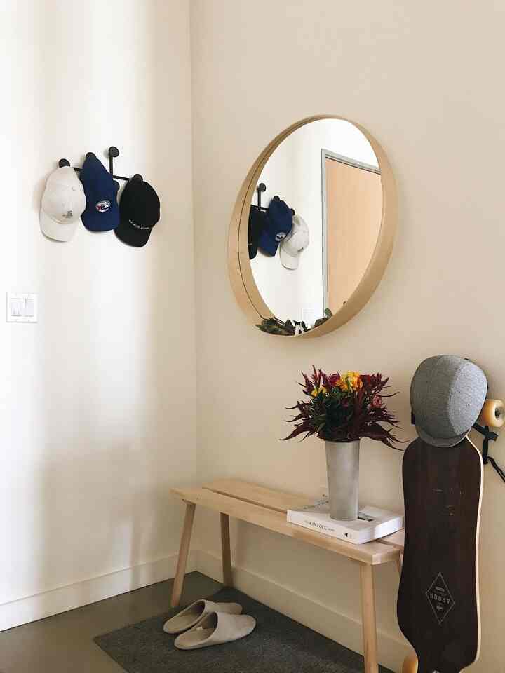 Wood tone and white entrance corner featuring a bench and round mirror in a cozy entryway